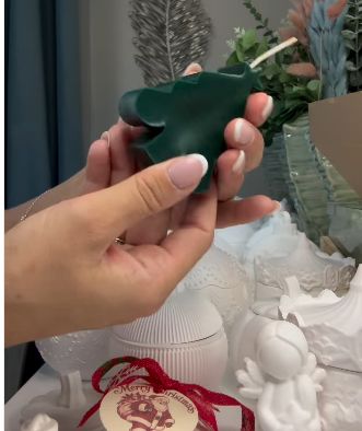 The finished Christmas tree candle, held by its maker.